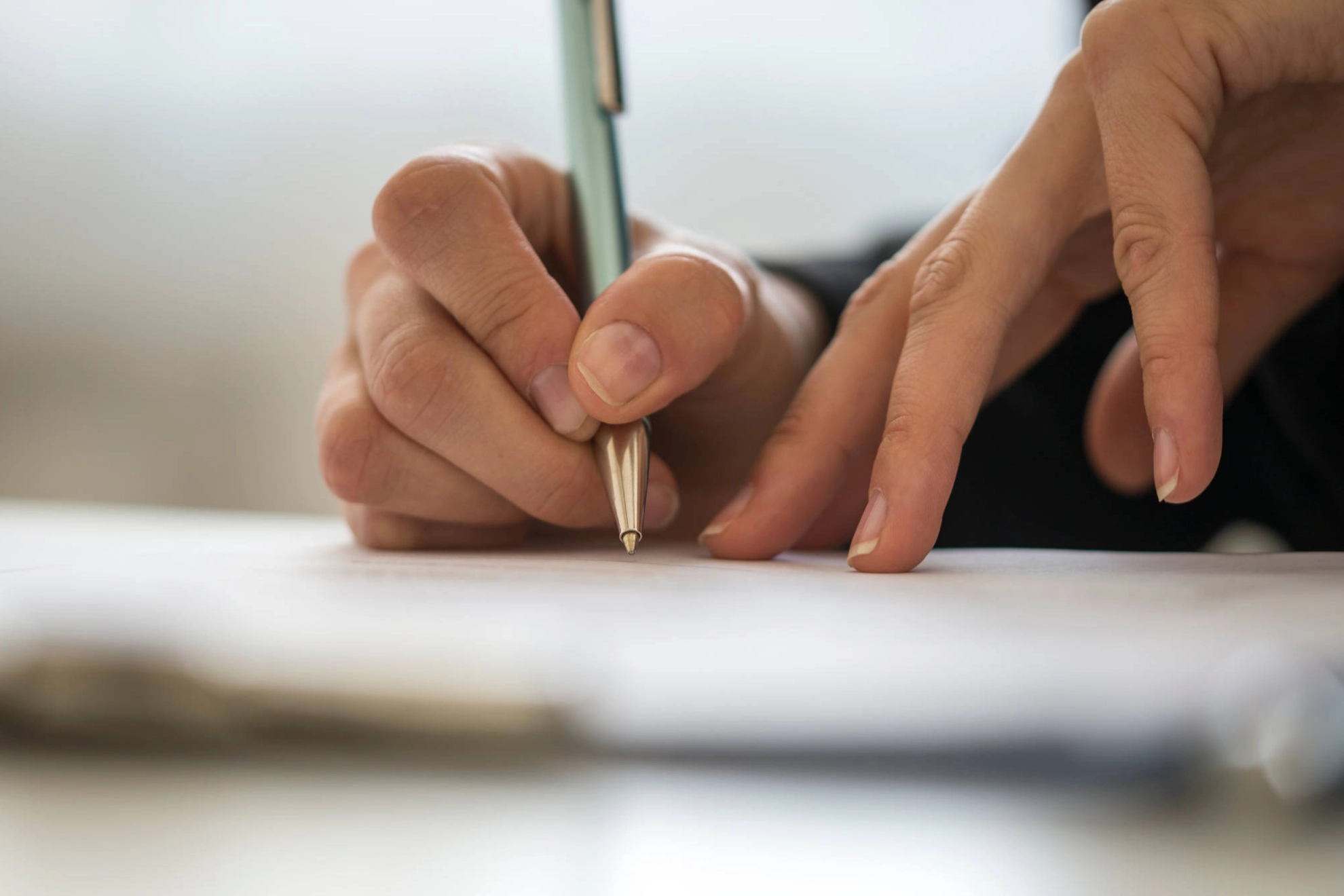 Jemand schreibt etwas auf ein Stück Papier.